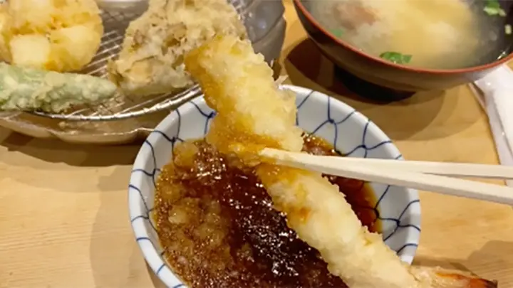 海老の天ぷらを箸で持ち上げている写真
